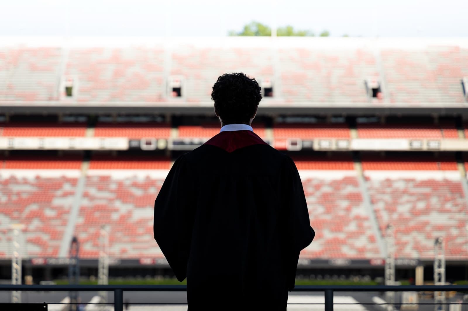 A quiet look back at the field, gown silhouetted against the stands