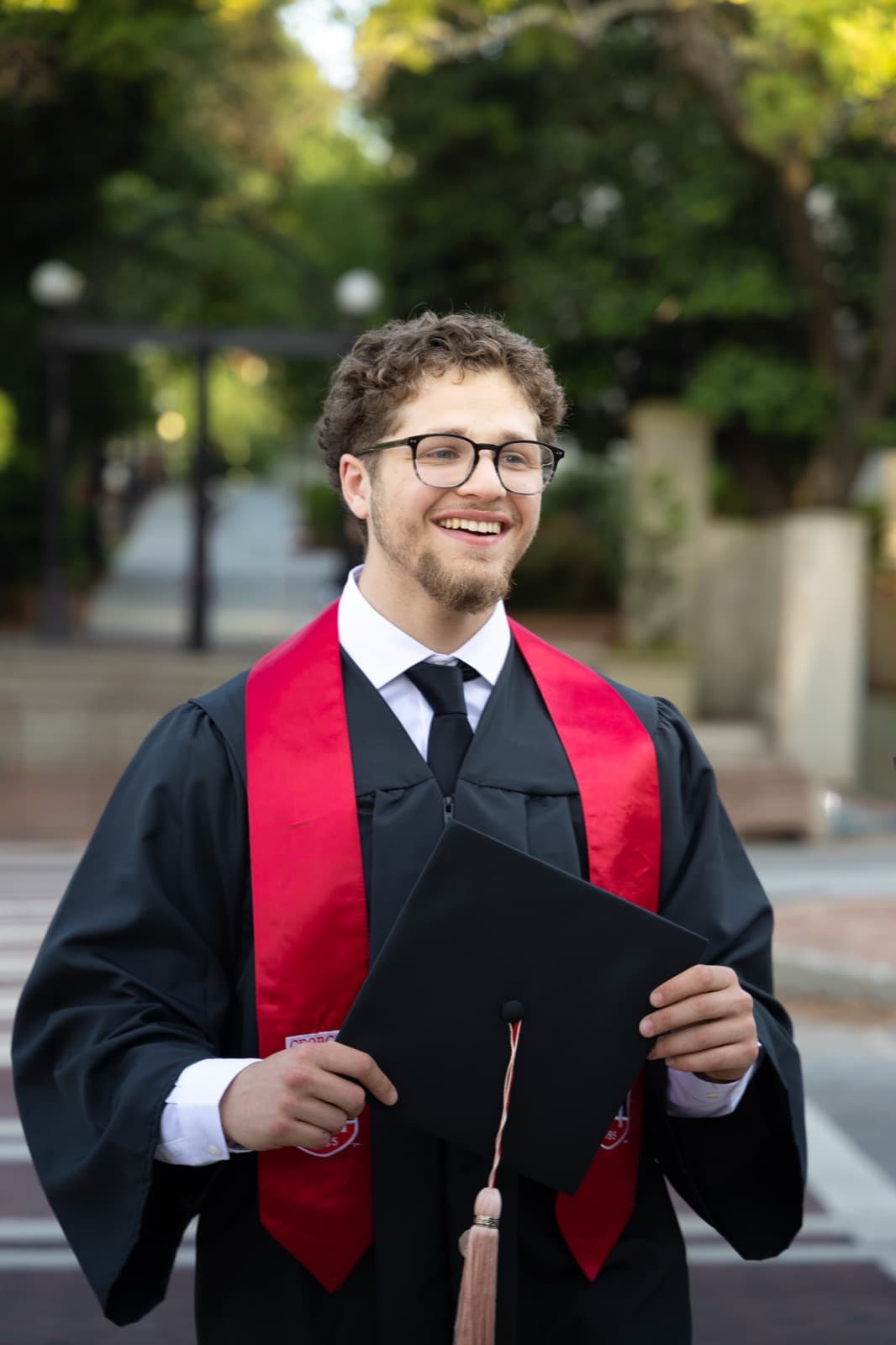 Cap in hand on the campus walkway between locations